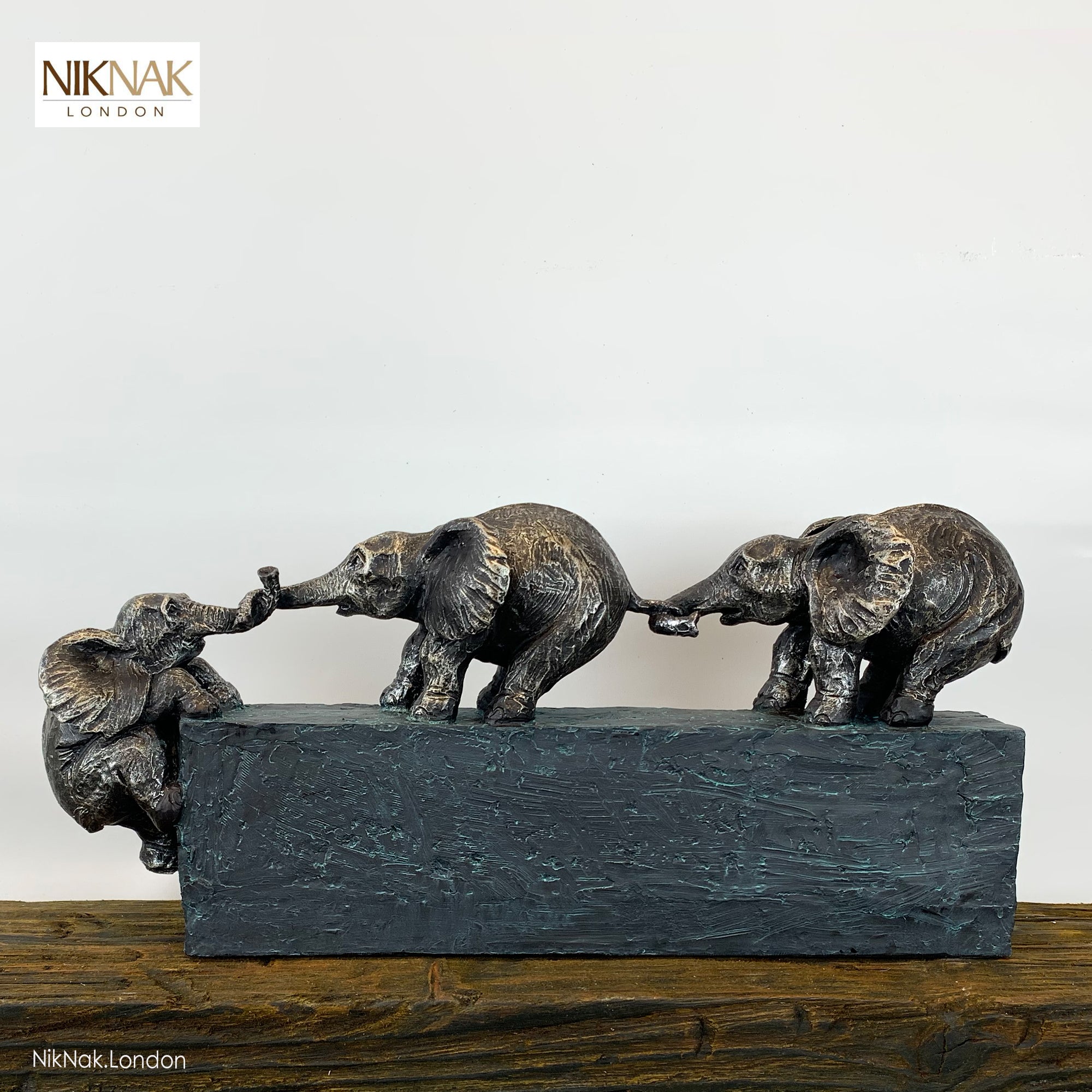 3 Elephants climbing over a stone block