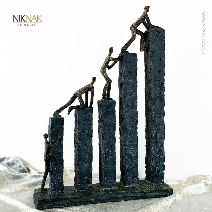 Bronze and slate styled sculpture of men climbing over blocks