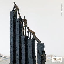 rear view of Bronze and slate styled sculpture of men climbing over blocks